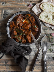 Beef stew in a frying pan on a wooden rustic table. Top view