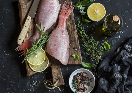 Fresh raw ruby snapper, herbs and spices on a dark background. Cooking dinner