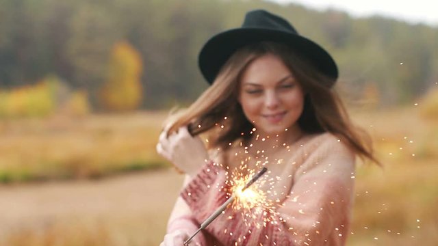 Beautiful girl holds sparklers in the forest. Autumn, outdoors