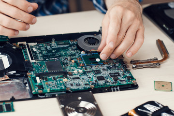Laptop disassembling in repair shop, close-up. Disassembled computer motherboard on repairman workplace. Electronic development, technology fixing concept