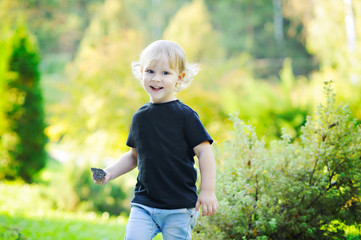 Portrait of a laughing boy on the nature, curly blond hair, black t-shirt.