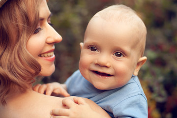 Young beautiful woman mom holding cheerful baby 6 months, summer