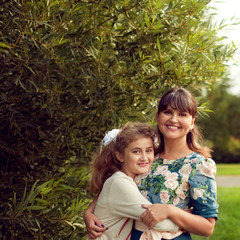 Beautiful young mother in a floral dress and daughter teen 10 ye