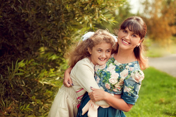 Fototapeta premium Beautiful young mother in a floral dress and daughter teen 10 ye