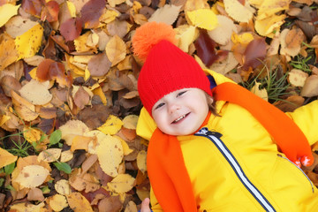 kid in autumn laying in leaves