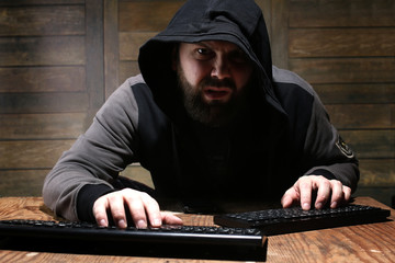 hacker in the black hood in a room with wooden walls