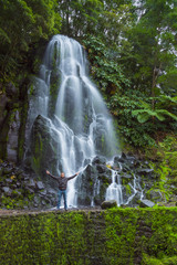 man with open arms in front of a big waterfall