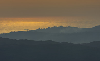 mountain with the ocean in the horizon and a ship