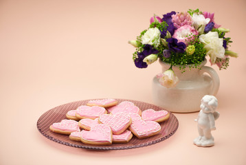 Obraz na płótnie Canvas pink cookies in the shape of hearts on a plate with angels and flowers on Valentine's Day