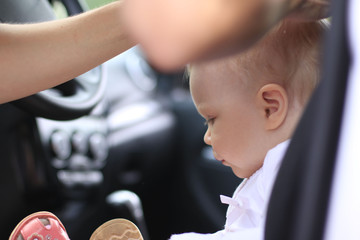 Sad baby in the car and the woman's hands are making the hair st