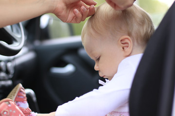Sad baby in the car and the woman's hands are making the hair st