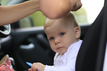 Sad baby in the car and the woman's hands are making the hair st