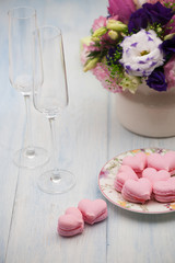 Obraz na płótnie Canvas pink cookies in the shape of hearts on a plate and glasses of champagne with flowers on wooden boards on Valentine's Day