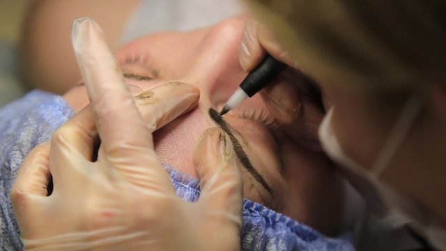 Cosmetologist applying permanent make-up. Old beautiful woman having cosmetic tattoo on her eyebrow. Beauty salon for women. Cosmetic tattoo.