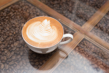 Cup off coffee on glass table with coffee bean.
