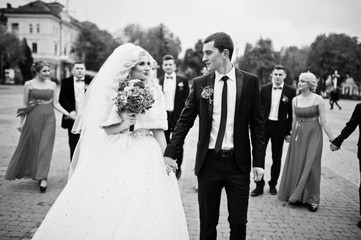 Newlyweds walking backgound bridesmaids and groomsman