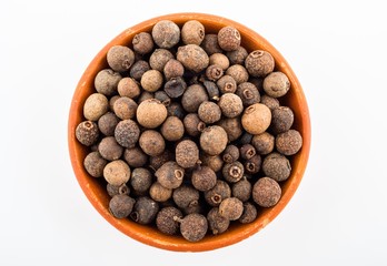 Allspice berries in light brown ceramic bowl