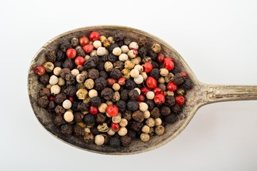 Mixed peppercorns in rustic silver spoon.