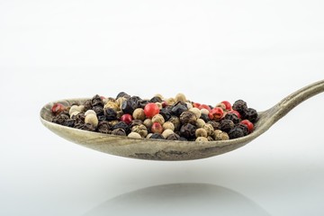 Mixed peppercorns in rustic silver spoon.