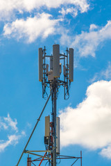 Mobile phone communication tower with devices on blue sky