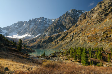 Panoramic view from above on the smooth mirror like surface of the turquoise mountain lake Kuyguk and green larches, which is located at the begining of the mountain pass, Altai