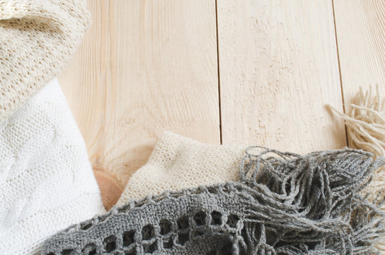 Cozy and soft winter background. Warm knitted clothes on a wooden background.