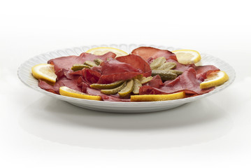 bresaola cetriolini  e limone in piatto primo piano