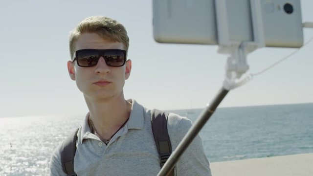Traveller taking emotionless selfie by stick