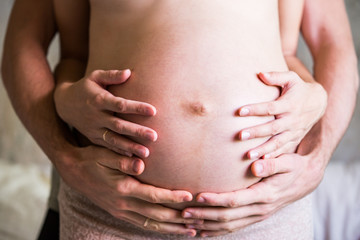 Husband's and wife's hands on a pregnant belly