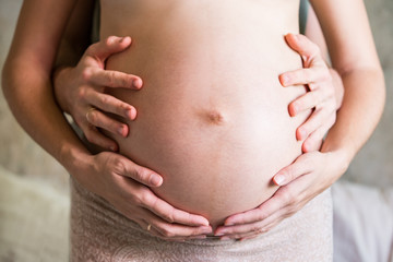 Husband's and wife's hands on a pregnant belly