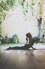 Portrait of gorgeous young woman practicing yoga indoor. Beautiful girl practice cobra asana in class.Calmness and relax, female happiness.Vertical, blurred background.