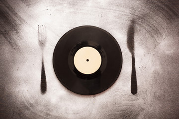 Vinyl record in the form of plates on the silhouette fork and knife. Good taste in music
