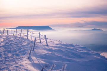 Ice-covered fence at the top of a mountain in the sunset