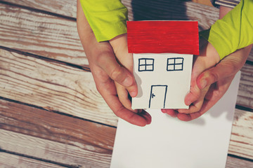 Hands holding paper house