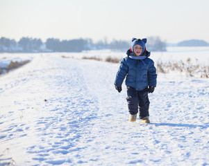Fototapeta na wymiar Baby boy running on road at cold winter day 
