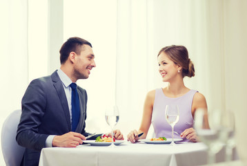 Fototapeta premium smiling couple eating main course at restaurant