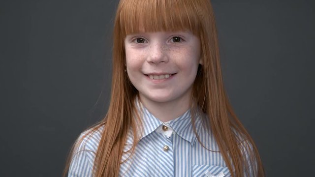 Little ginger girl quickly coming close up to the camera, gray background