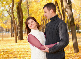 Fototapeta premium romantic people, happy adult couple embrace in autumn city park, trees with yellow leaves, bright sun and happy emotions, tenderness and feelings