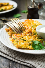 Pancakes with cabbage and spinach on a white ceramic plate on old wooden background. Rustic style. Selective focus.