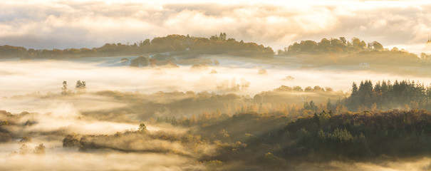 Aerial view of valley covered in layers of fog on a beautiful Autumn morning in the Lake District.