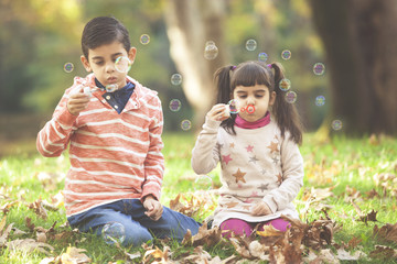 Kids having fun blowing soap bubbles in the park