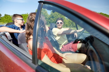 happy friends driving in cabriolet car and talking