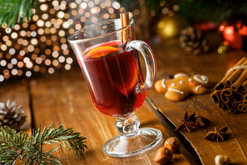 Glass of mulled wine by Christmas tree. Traditional delicious drink for New Year party