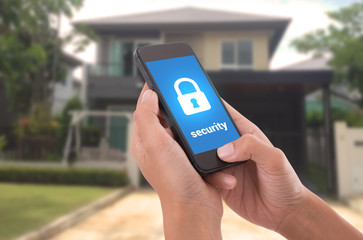 Hand holding mobile phone with concept technology home security system.