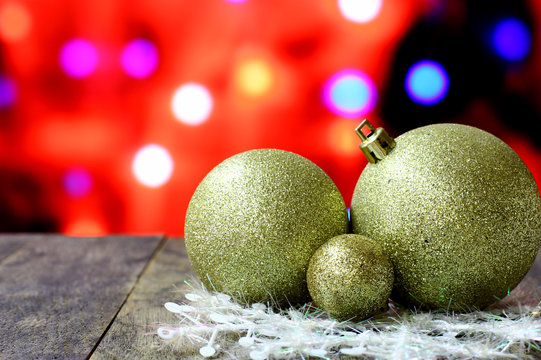 Christmas background with gold balls decorations on old dark wooden desk table. Colorful holiday bokeh garland lights. Wood foreground and ready for product montage. 