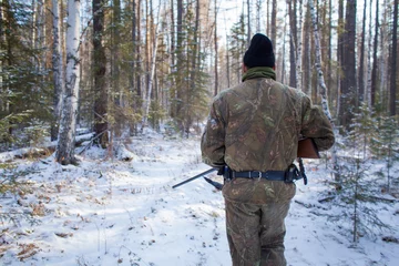  a hunter in the winter woods with a gun in camouflage clothing. © nikstar_2012