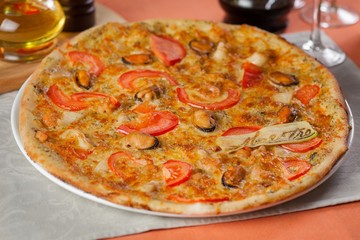 Italian pizza with tomatoes and mushrooms on a plate