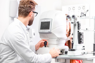 Eye doctor checking vision with modern ophthalmologic device in the cabinet