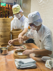 Two chefs in white uniforms preparing a dish of dough in a clean little kitchen (Singapore)