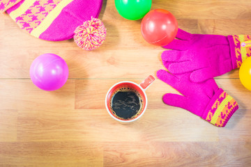 Top view gloves, Silk hat, colored balls and a cup of coffee on wood table. In the winter. Warm up with hot coffee, sunlight helps the body to warm up.